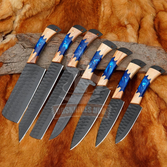 Handmade Damascus knives with blue resin and wood handles, hammered finish blades on fur and wood