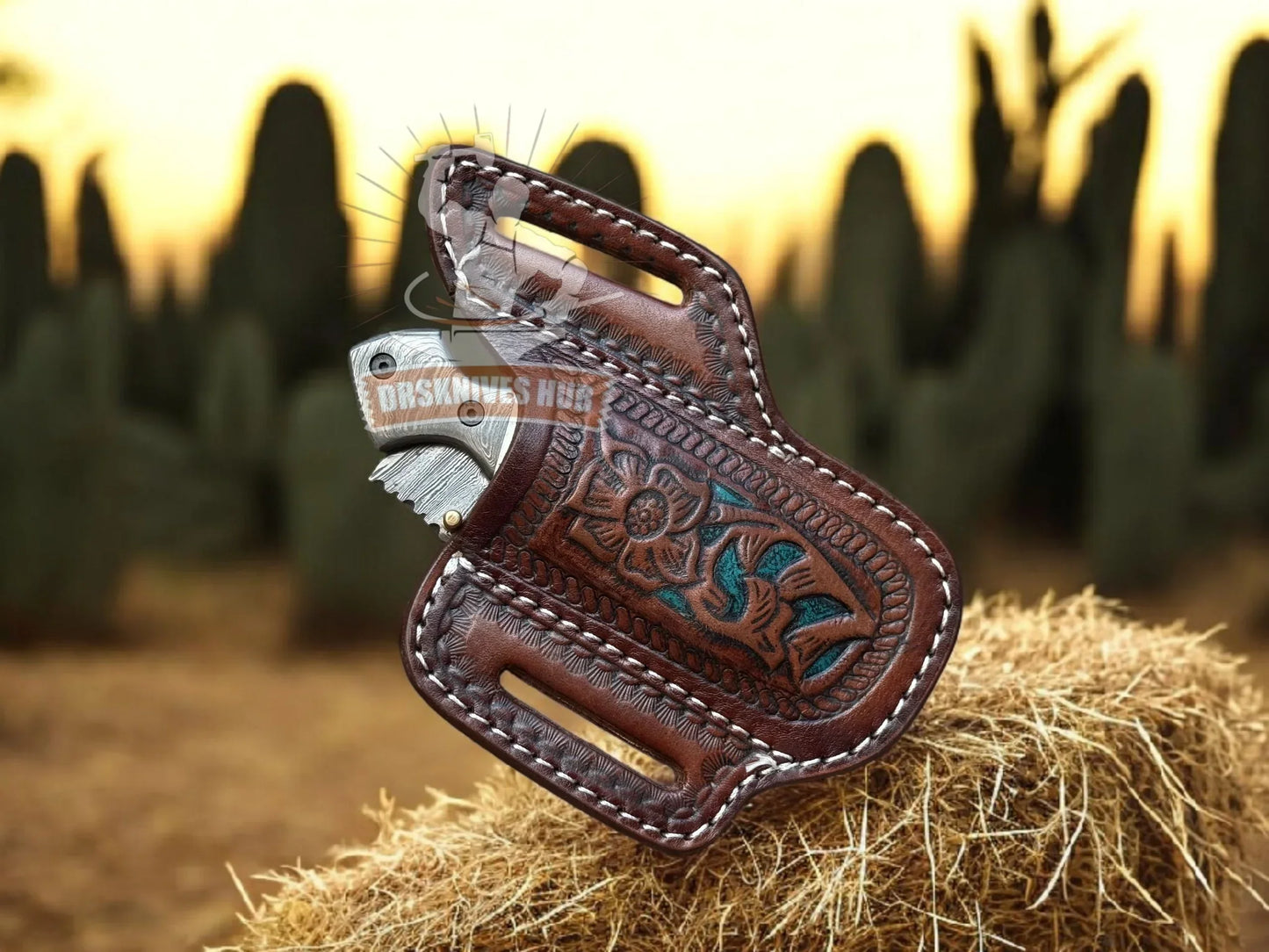 Handmade Damascus knife in tooled leather sheath with turquoise inlay, set against desert cactus backdrop