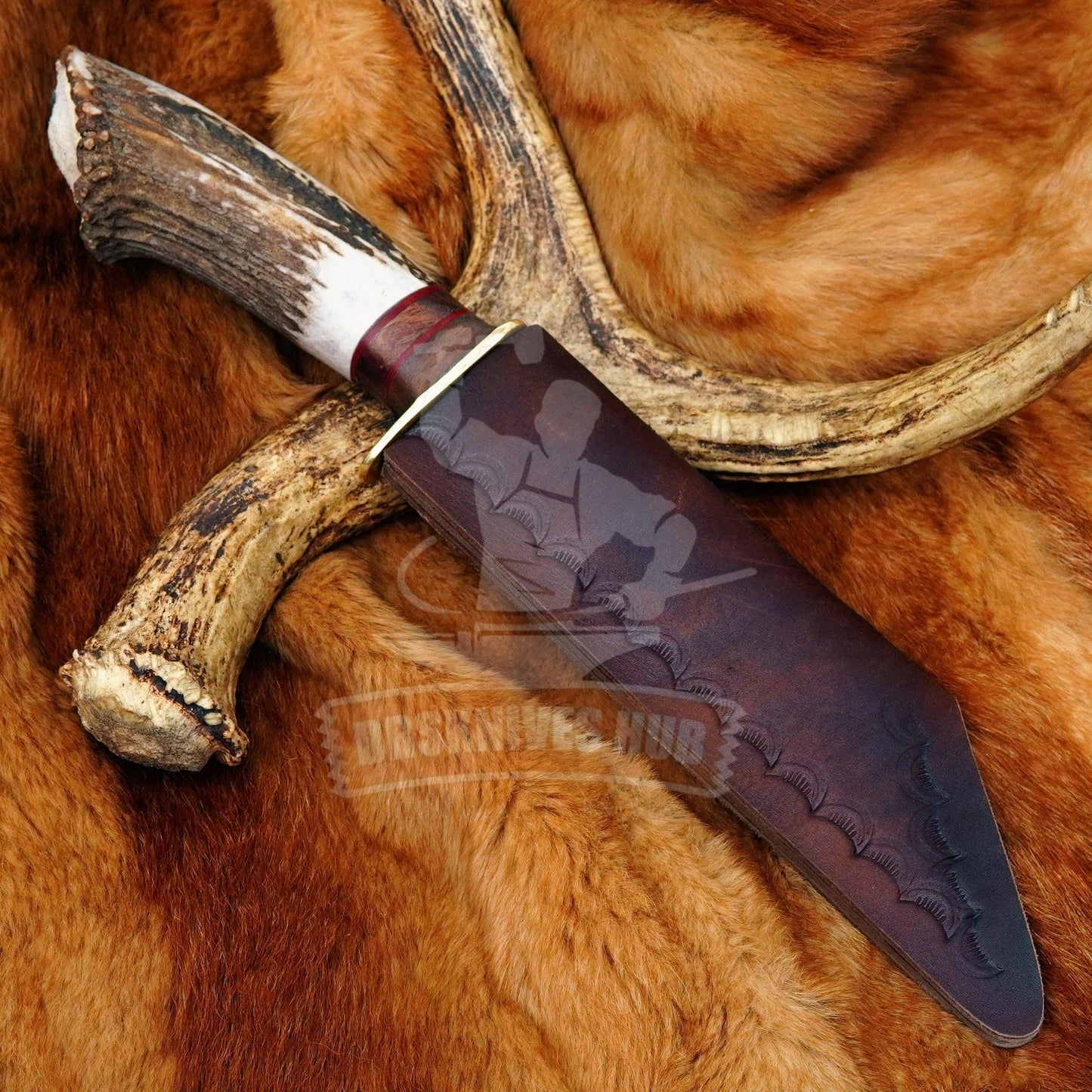 Handmade Damascus knife with antler handle and leather sheath on fur background