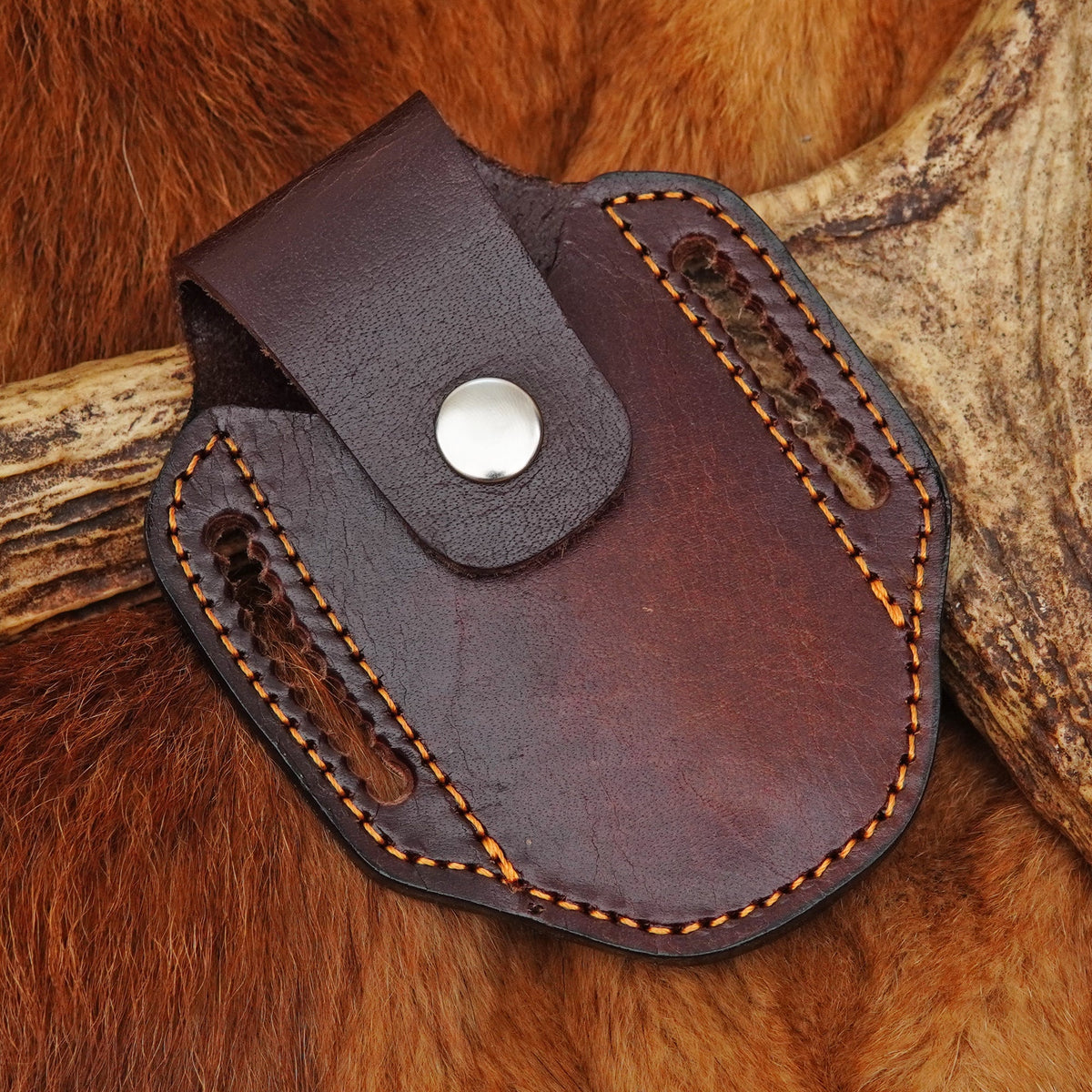 A dark brown leather knife sheath with orange contrast stitching and a silver snap button
