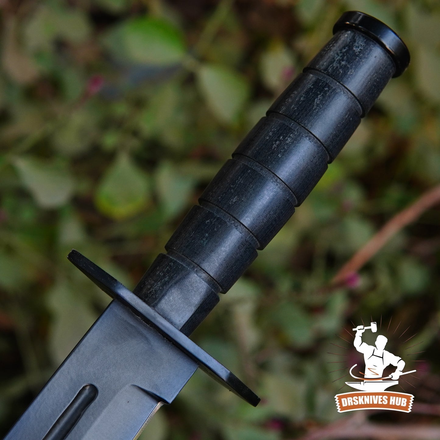 Black knife with textured handle against a blurred natural background