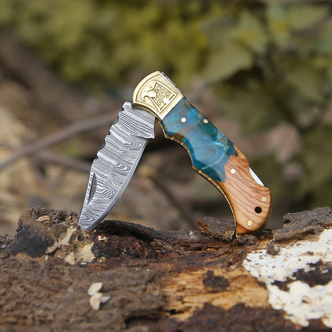 A folding knife featuring a Damascus steel blade and Resin handle, accompanied by a leather sheath cover.