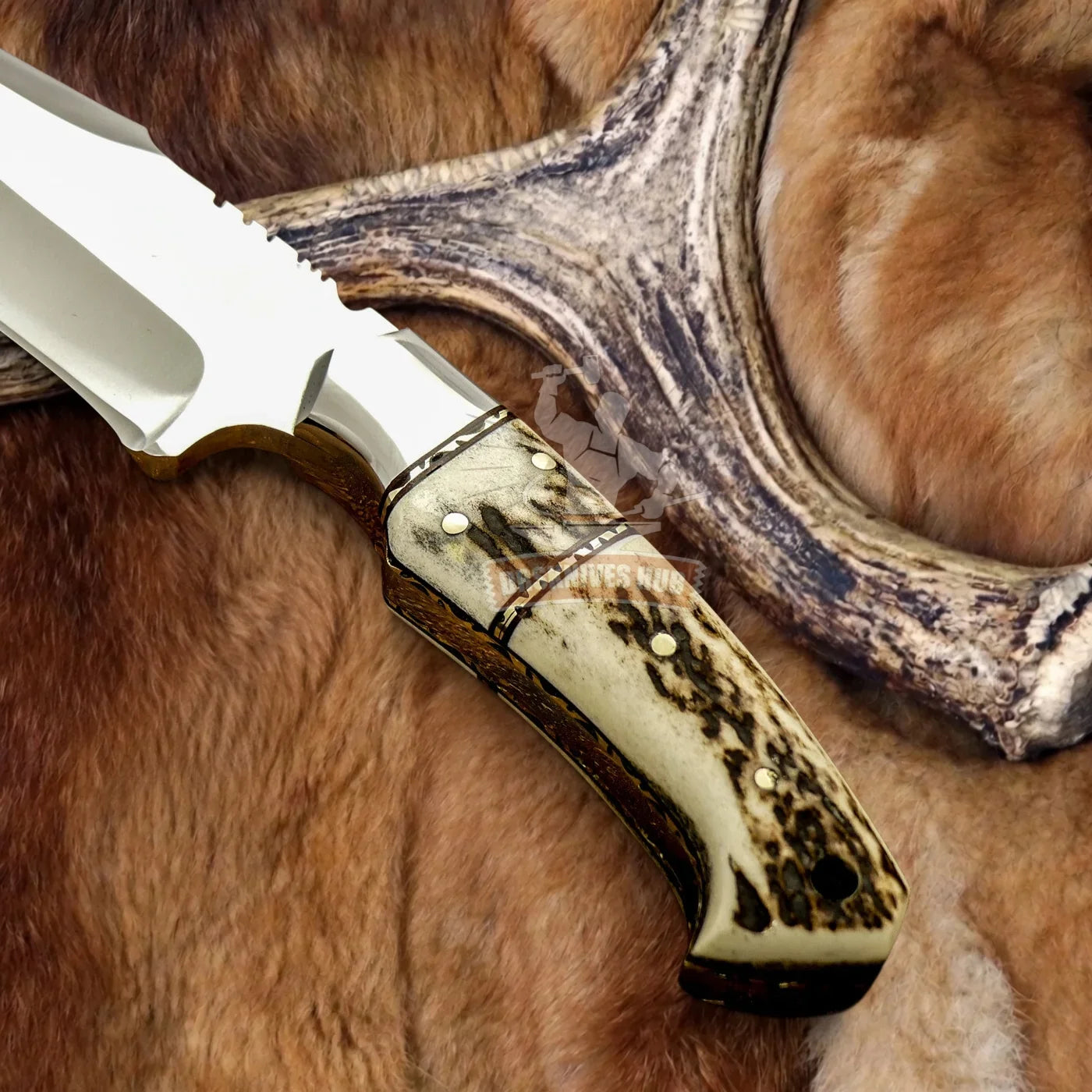 Handmade Damascus hunting knife with stag horn handle, resting on fur and antler