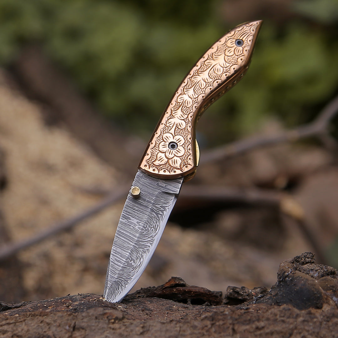 A pocket knife featuring a Damascus steel blade and a copper handle