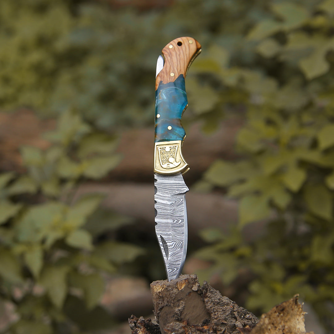 A folding knife featuring a Damascus steel blade and Resin handle, accompanied by a leather sheath cover.