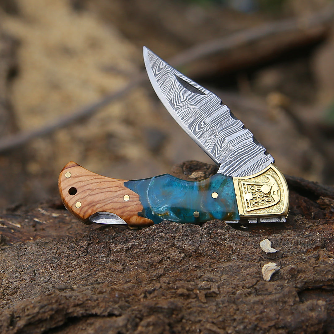 A folding knife featuring a Damascus steel blade and Resin handle, accompanied by a leather sheath cover.