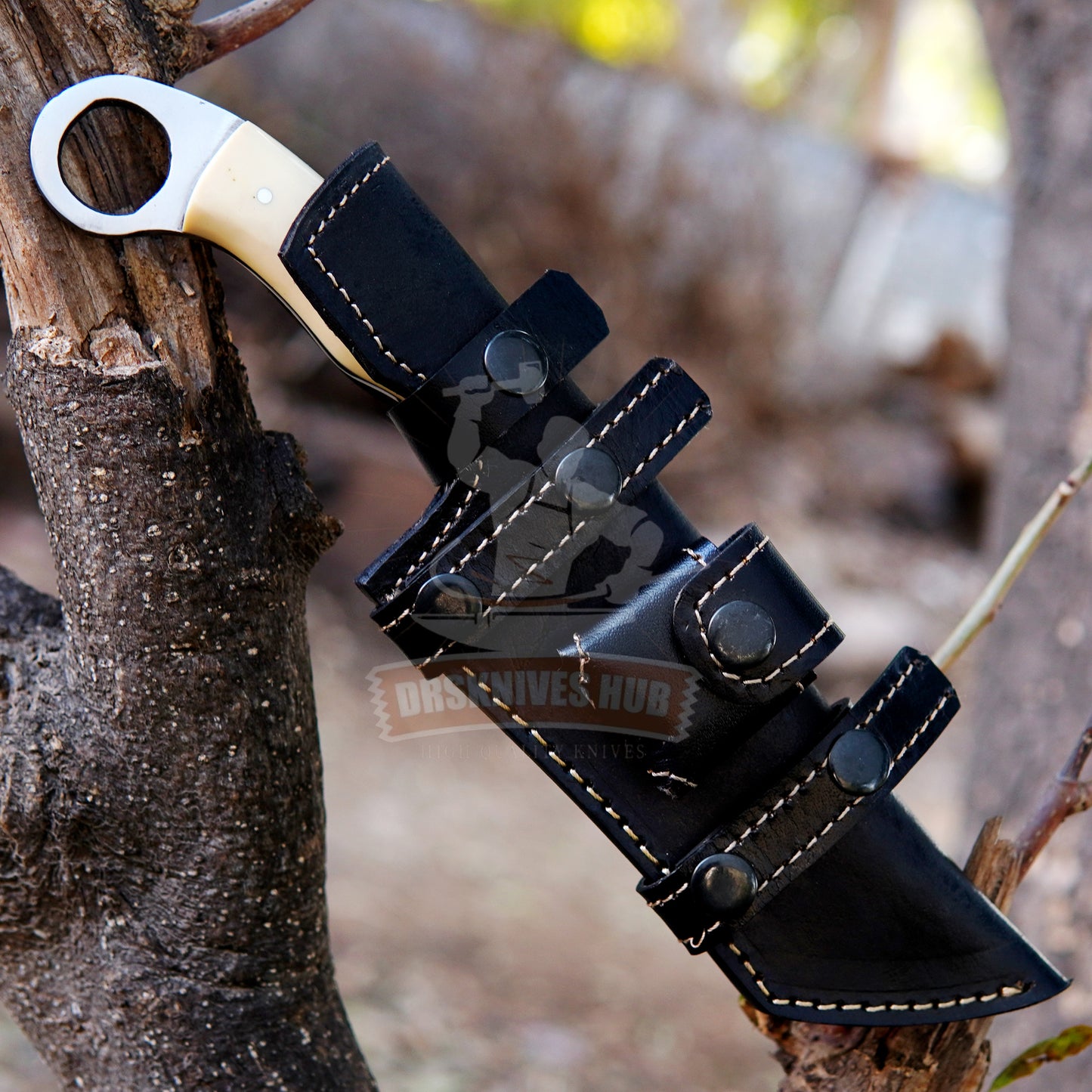 Black leather archery quiver with a bow nocking tool attached to a tree branch.